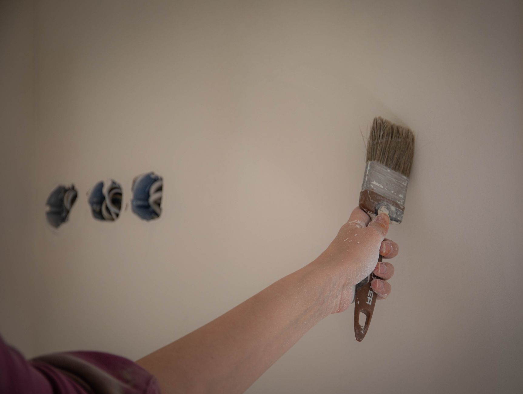 A person painting a wall with a brush, showcasing a home makeover process in Carlsbad, CA